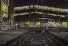 Verlassene Industriehalle mit Graffiti und Müll.