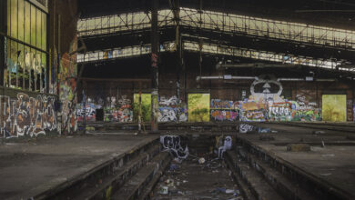 Verlassene Industriehalle mit Graffiti und Müll.