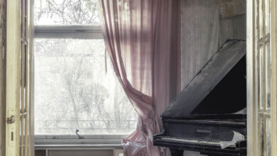 Verlassenes Zimmer mit Klavier und rosa Vorhängen.